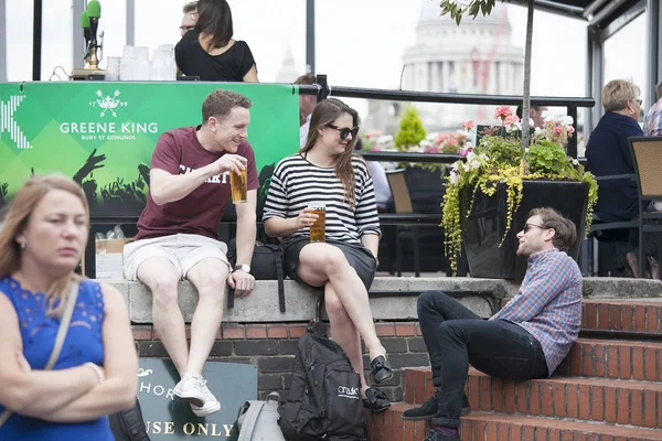 Una multitud heterogénea se sienta fuera del pub, bebe cerveza, habla con amigos. Southbank. — Foto de Stock