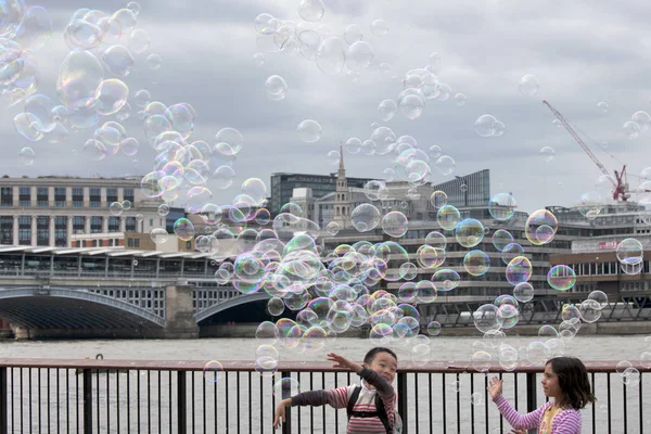 子供たちはロンドンの背景に石鹸の泡をキャッチします。 — ストック写真