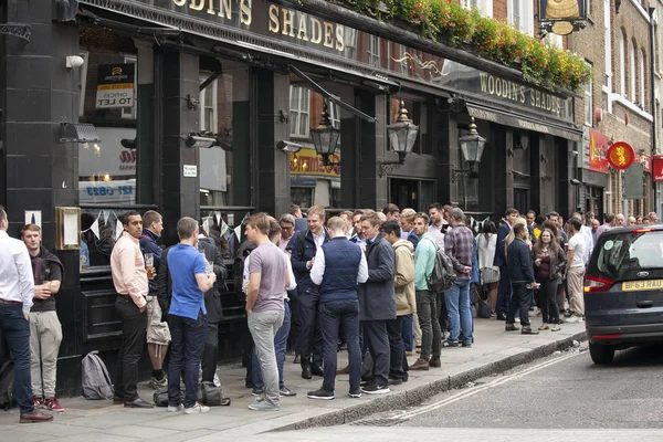 Rengarenk kalabalık pub dışında oturur, bira içiyor, arkadaşlarıyla konuşuyor. Semt pazarı