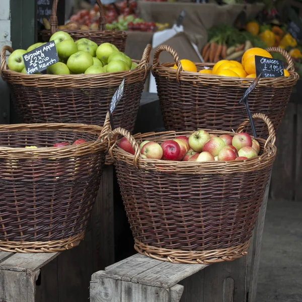 Las Diferentes variedades de las manzanas en las cestas de mimbre para la venta en el mercado otoñal — Foto de Stock