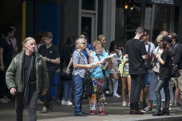 A nagy tömeg, a turisták, a Piccadilly Circus területen. Egy idős házaspár figyelembe véve, a város megjelenítése. — Stock Fotó