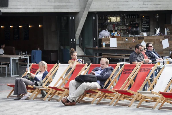 La gente lee libros sentados en tumbonas cerca del Teatro Nacional — Foto de Stock