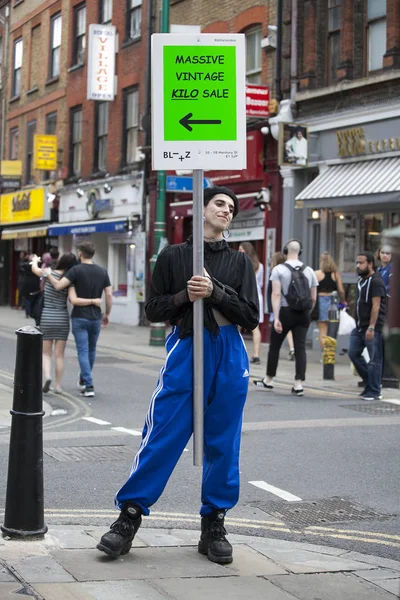 bir reklam posteri ile erkek organizatörü Bricklane asfaltta ortasında duruyor