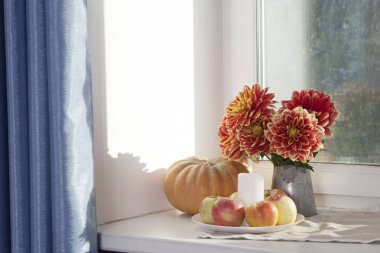 Teneke bir kavanoz, kabak, bir fincan çay ve güneşli havalarda penceresinde üzerinde elma kırmızı dahlias ile sonbahar natürmort