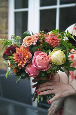 Kırmızı dantel elbise gelin dahlias ve gül buket tutar