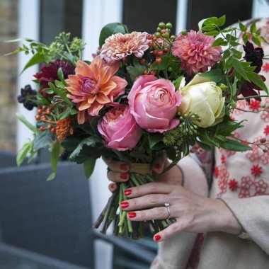 Kırmızı dantel elbise gelin dahlias ve gül buket tutar