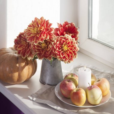 Teneke bir kavanoz, kabak, bir fincan çay ve güneşli havalarda penceresinde üzerinde elma kırmızı dahlias ile sonbahar natürmort