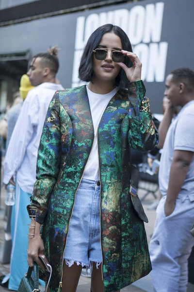 A girl with glasses and a green jacket, denim shorts