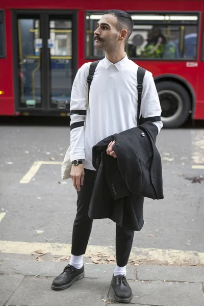 Ένα hipster άνδρα με μουστάκι σε ένα λευκό πουλόβερ και το μαύρο στενό παντελόνι — Φωτογραφία Αρχείου