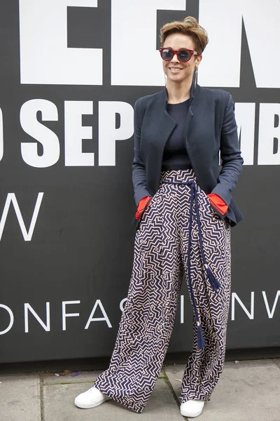 Güzel ve şık bir kız bir siyah ceket ve Londra Moda Haftası sırasında poz renkli kahverengi pantolon teşkil etmektedir. Dış Eudon Choi