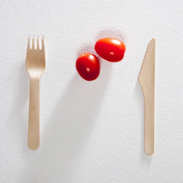 El tenedor con el cuchillo dos tomate cereza sobre el fondo blanco . — Foto de Stock