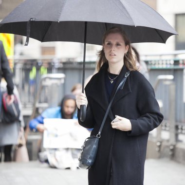 Güzel bir kız bir şemsiye altında Londra sokaklarında yürüyor