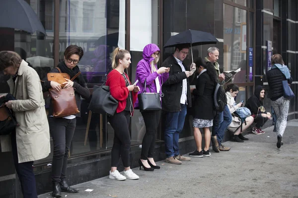 Las personas después del trabajo se paran bajo el paraguas contra la pared, esperándose unas a otras . — Foto de Stock