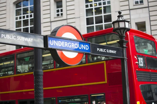 Вход в метро с надписью "Underground" на фоне красного двухэтажного автобуса — стоковое фото