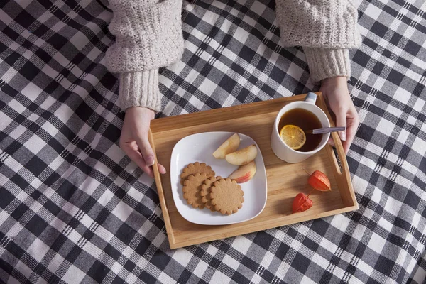 Zásobník s šálkem čaje a talíř s zázvorové sušenky a apple na kostkovaný přehoz — Stock fotografie