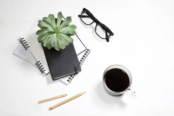 A vista superior do desktop branco do escritório com planta, xícara de café, óculos e artigos de papelaria. Faz asneira. — Fotografia de Stock