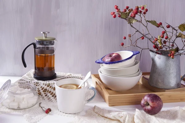 Natürmort bir alıç, bir fincan çay ve bir su ısıtıcısı Beyaz ahşap zemin üzerinde — Stok fotoğraf