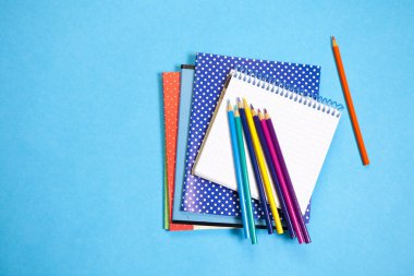 bir defter üzerinde mavi arka plan ile çeşitli okul teçhizatı