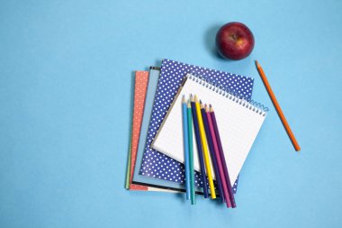 bir defter üzerinde mavi arka plan ile çeşitli okul teçhizatı