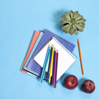 bir defter üzerinde mavi arka plan ile çeşitli okul teçhizatı