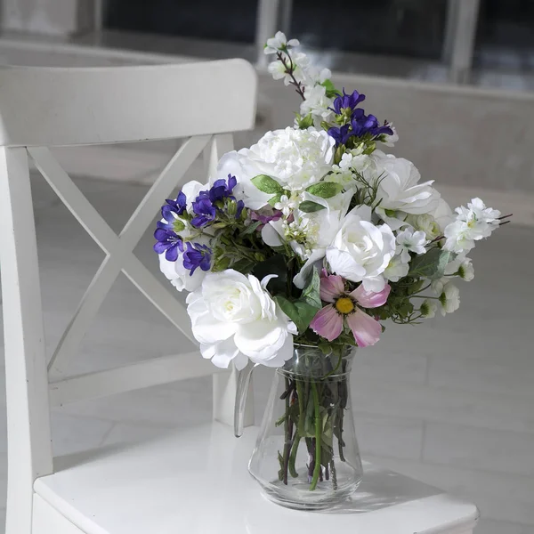 El Ramo de las rosas artificiales, el flex y las campanas sobre la mesa en el florero, como la decoración interior —  Fotos de Stock
