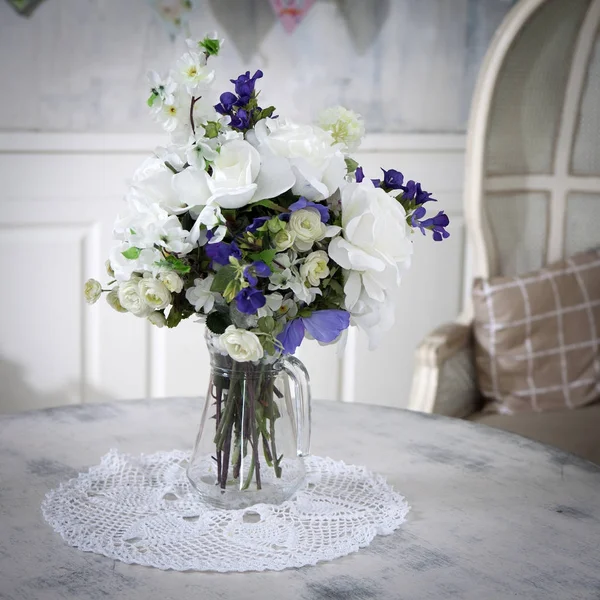 El Ramo de las rosas artificiales, el flex y las campanas sobre la mesa en el florero, como la decoración interior —  Fotos de Stock