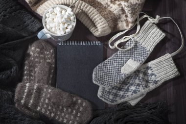 Yün eldiven, eşarp ve kazak notlar için siyah bir not defteri ile masaya yalan. Kopya alanı.