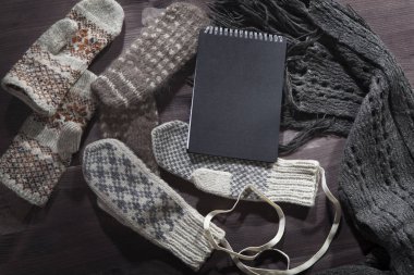 Yün eldiven, eşarp ve kazak notlar için siyah bir not defteri ile masaya yalan. Kopya alanı.