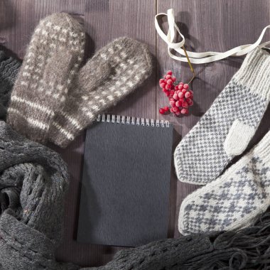 Yün eldiven, eşarp ve kazak notlar için siyah bir not defteri ile masaya yalan. Kopya alanı.