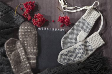 Yün eldiven, eşarp ve kazak notlar için siyah bir not defteri ile masaya yalan. Kopya alanı.