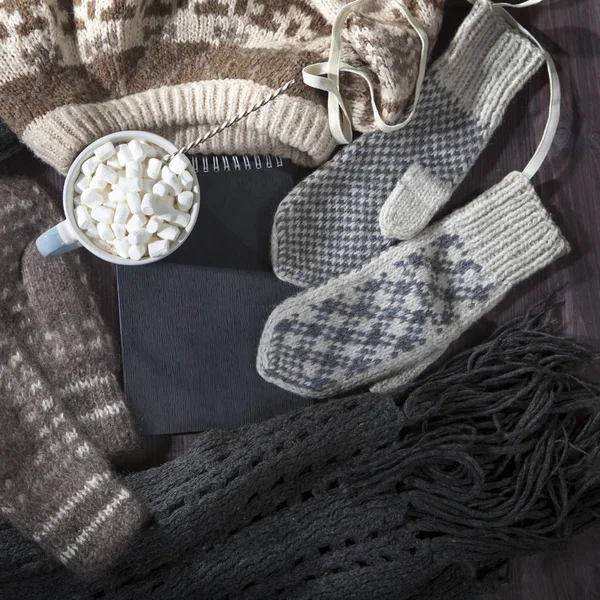 De wollen wanten en sjaal, trui met een zwarte Kladblok voor notities op de tafel liggen. Kopiëren van ruimte. — Stockfoto