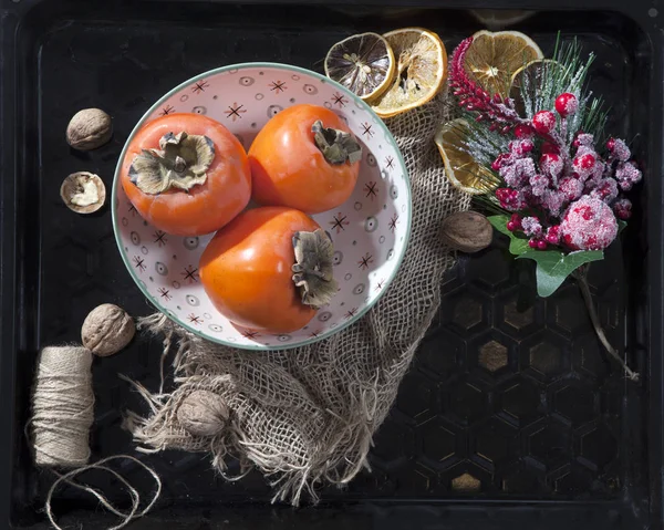 De kaki in een plaat op een servet gemaakt van doek op een donkere houten tafel — Stockfoto