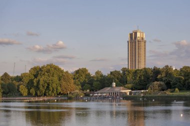 Hyde Park'ta bir modern gün batımında ufukta bina ile göl