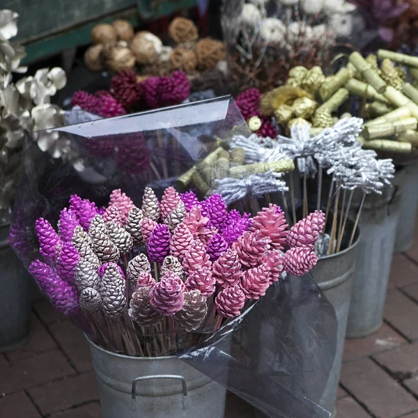 Kbelík se zlacenými skořicí a šišky na prodej na květinový trh. — Stock fotografie