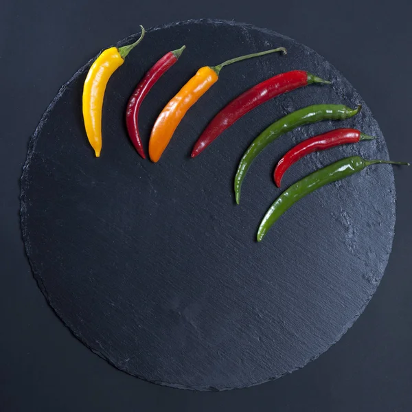 Chilipeppar på svart sten — Stockfoto