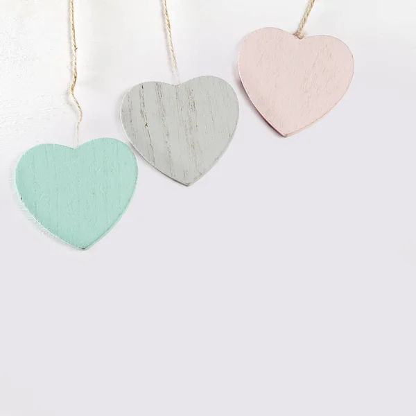 Tres corazones de madera cuelgan de una pared de madera blanca — Foto de Stock