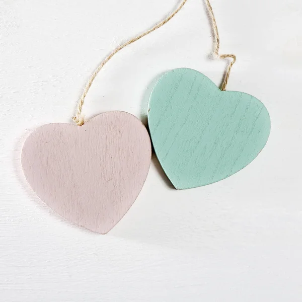 Two wooden hearts hang on a white wooden wall — Stock Photo, Image