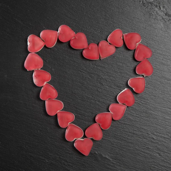 O marmelada vermelho corações em uma tábua de ardósia preta. Cartão de Dia dos Namorados — Fotografia de Stock