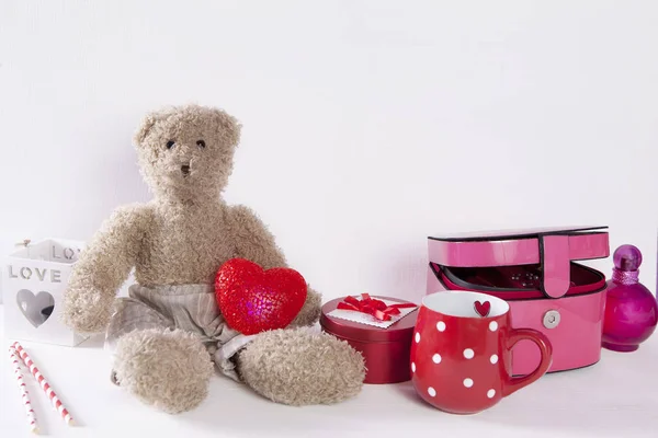 The Postcard to Valentine's day with teddy bear, red cup in the dots, light and casket on white wooden background — Stock Photo, Image