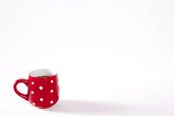 Červené cup v bílý bod je na bílý dřevěný stůl. Kopírovat prostor — Stock fotografie