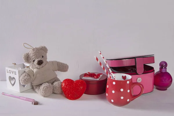 La Postal al día de San Valentín con el oso de peluche, la taza en los puntos, la luz y el ataúd sobre el fondo blanco de madera — Foto de Stock
