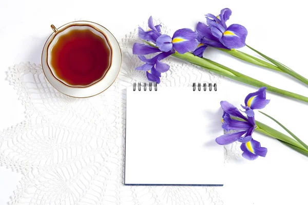 Los Lirios Violetas xiphium (Bulboso iris, sibirica) con la taza del té sobre el fondo blanco con el espacio para el texto. Vista superior, plana. Tarjeta de felicitación navideña para San Valentín, Día de la Mujer, Día de la Madre, Sabor —  Fotos de Stock