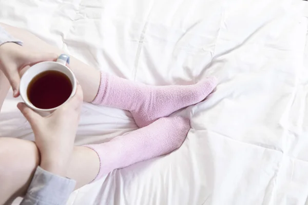 両手一杯のコーヒー。ピンクの靴下の中の足を見ることができます。. — ストック写真