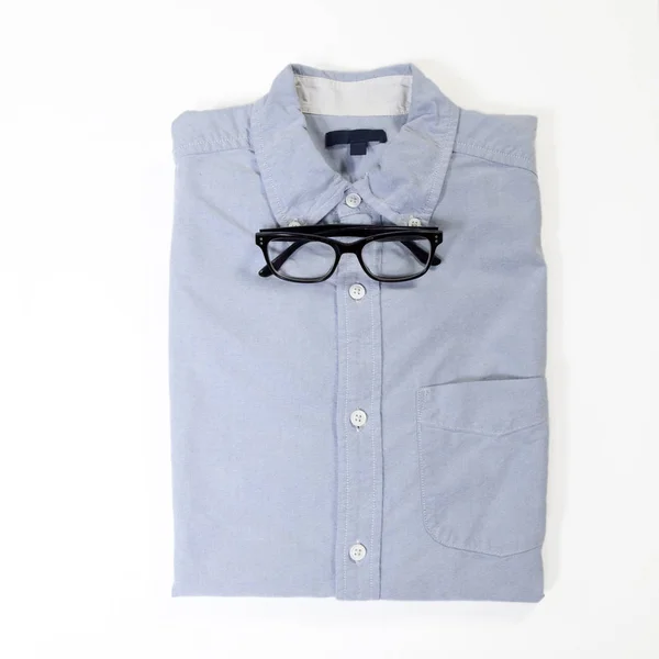 The glasses lie on the blue neatly folded men`s shirt with a long sleeve instead of a bow tie — Stock Photo, Image
