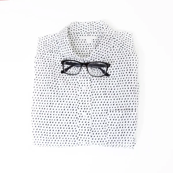 The glasses lie on the white neatly folded men`s shirt with a long sleeve instead of a bow tie — Stock Photo, Image