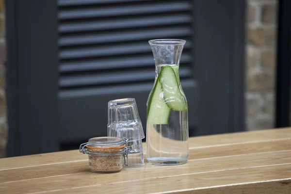 Láhev s vodou okurky a cukru na stole pouliční kavárny — Stock fotografie