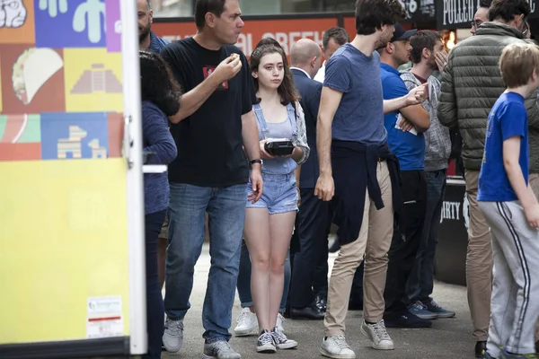 Ein Mädchen in Jeanshosen mit einer Kiste Lebensmittel kraxelt durch die Menge — Stockfoto
