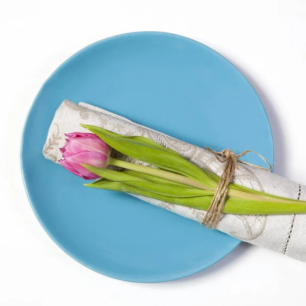 Grußkarte zum Valentinstag. Dekoration des Hochzeitstisches. auf einem blauen Teller eine Serviette mit einer Tulpe, schön gebunden. — Stockfoto