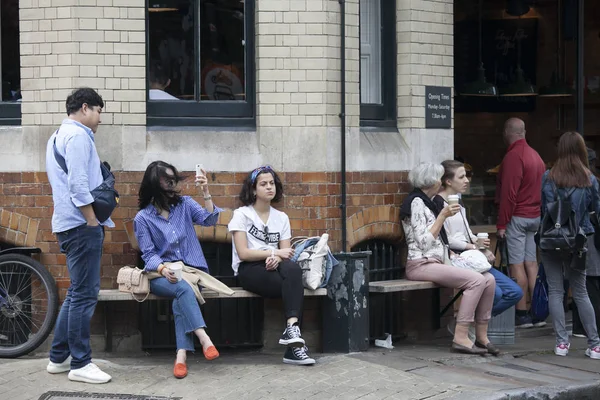 Jugendliche trinken Kaffee auf einer Bank in der Nähe eines Cafés — Stockfoto