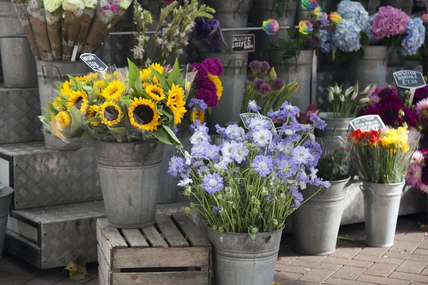 Kytice slunečnic a čekanky na prodej v blízkosti vchodu do květinářství. — Stock fotografie